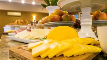 Un bufé con fruta amarilla en rodajas, queso y otros alimentos sobre una tabla de madera.