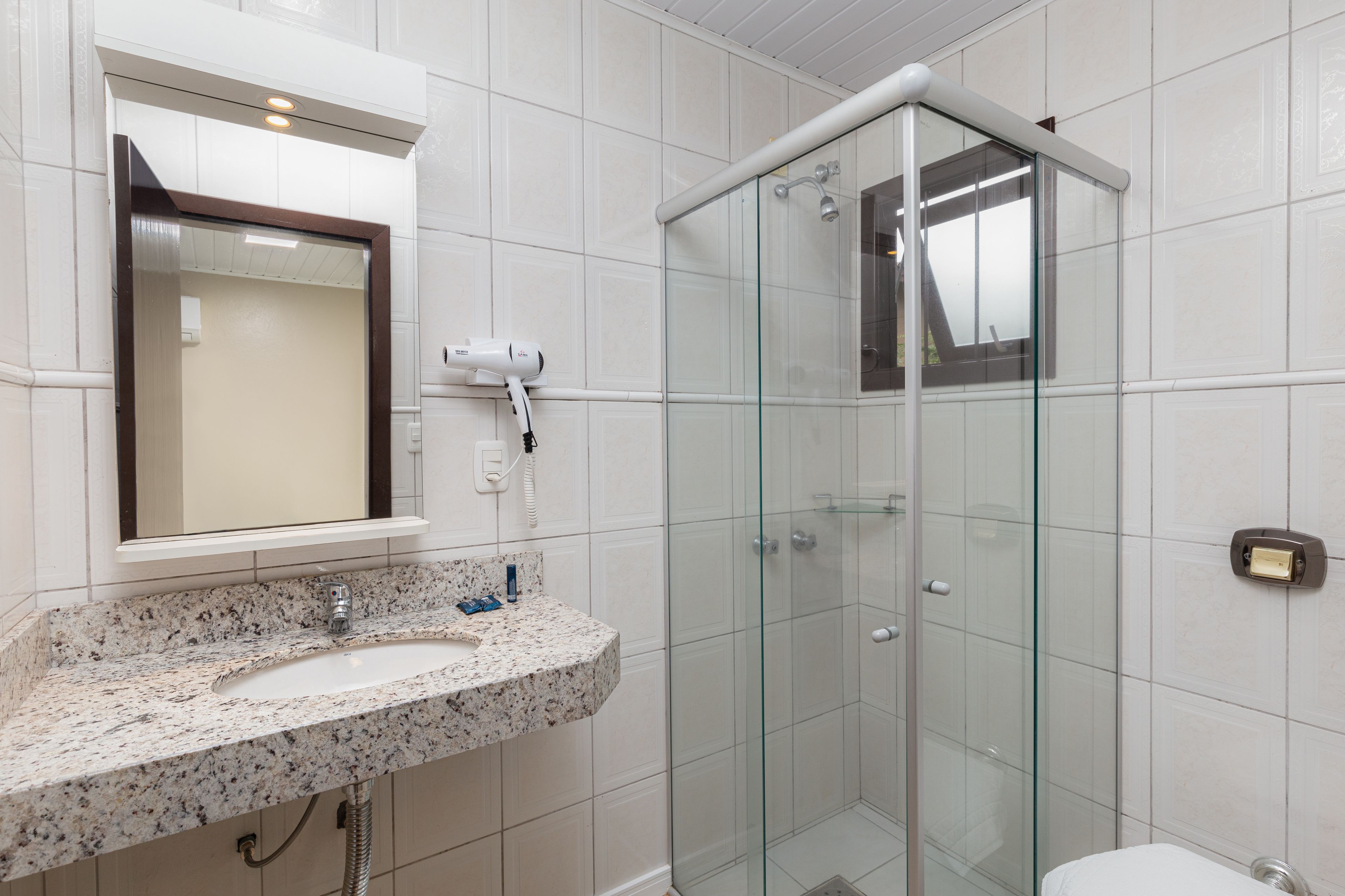 A bathroom with a granite countertop sink, a glass shower enclosure, and a toilet.