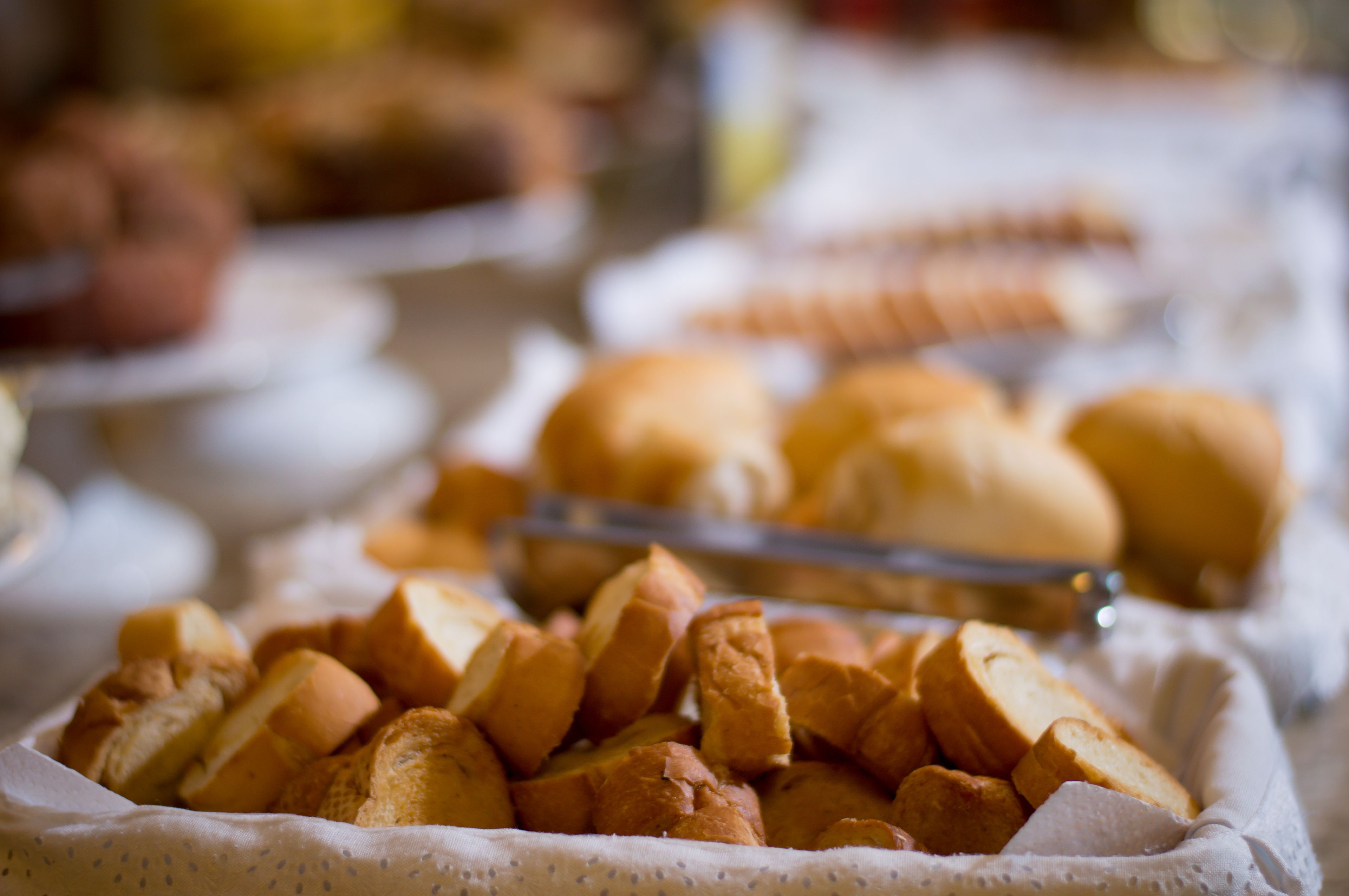 A buffet table with various food items, including bread rolls and sliced bread.