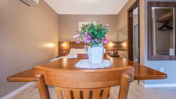 Un comedor con una mesa de madera, sillas, un jarrón de flores y un espejo en la pared.