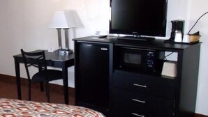 A hotel room with a bed, a desk with a television, a coffee maker, and a microwave. - Woodlawn Hills Motel (Henderson)
