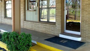 A building with a brick facade, large windows, and a covered entrance area with a bench. - Woodlawn Hills Motel (Henderson)