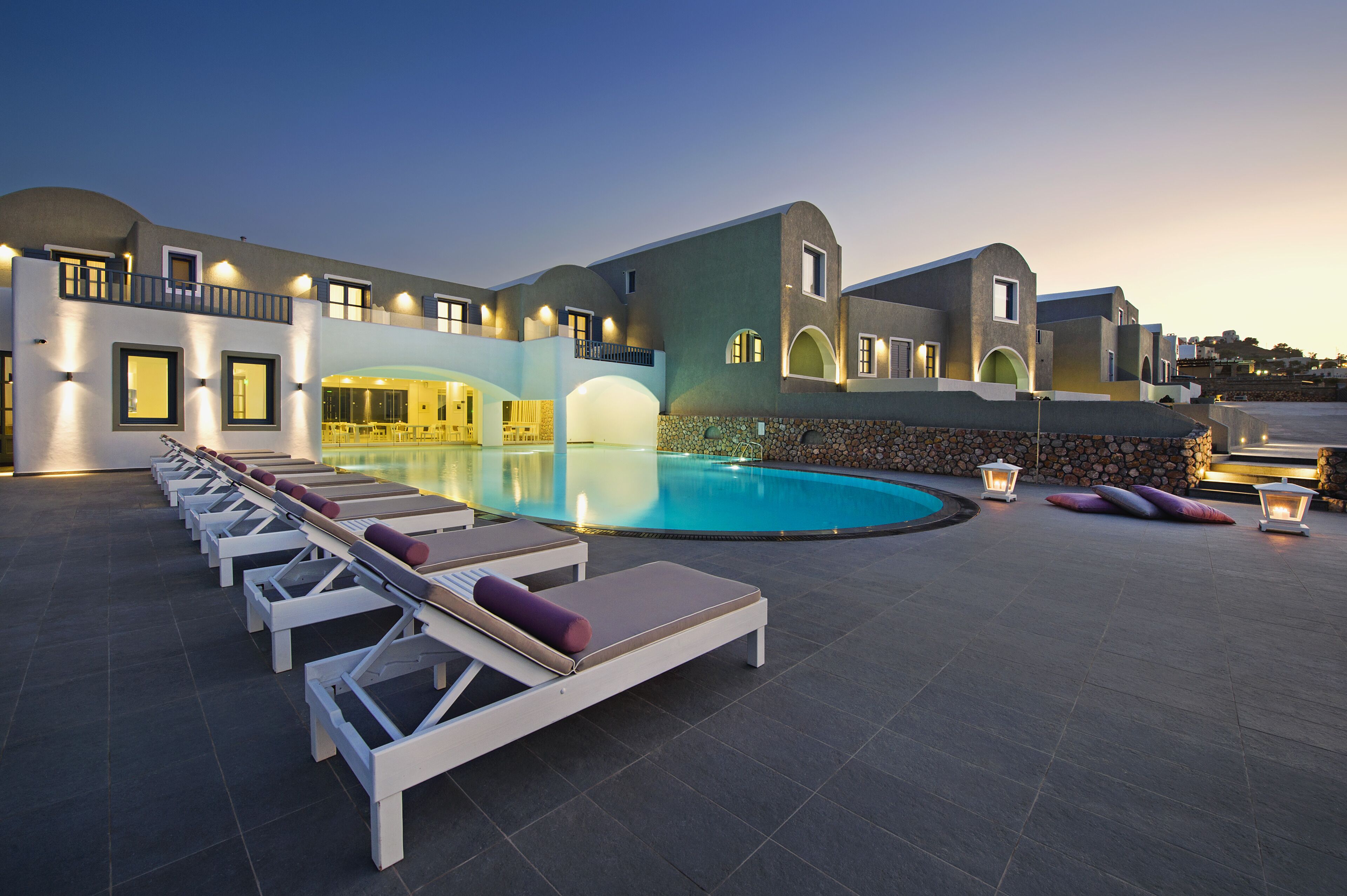 Un resort con piscina, lettini prendisole e un muro in pietra.