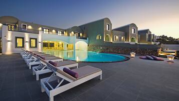 A resort with a swimming pool, sun loungers, and a stone wall.
