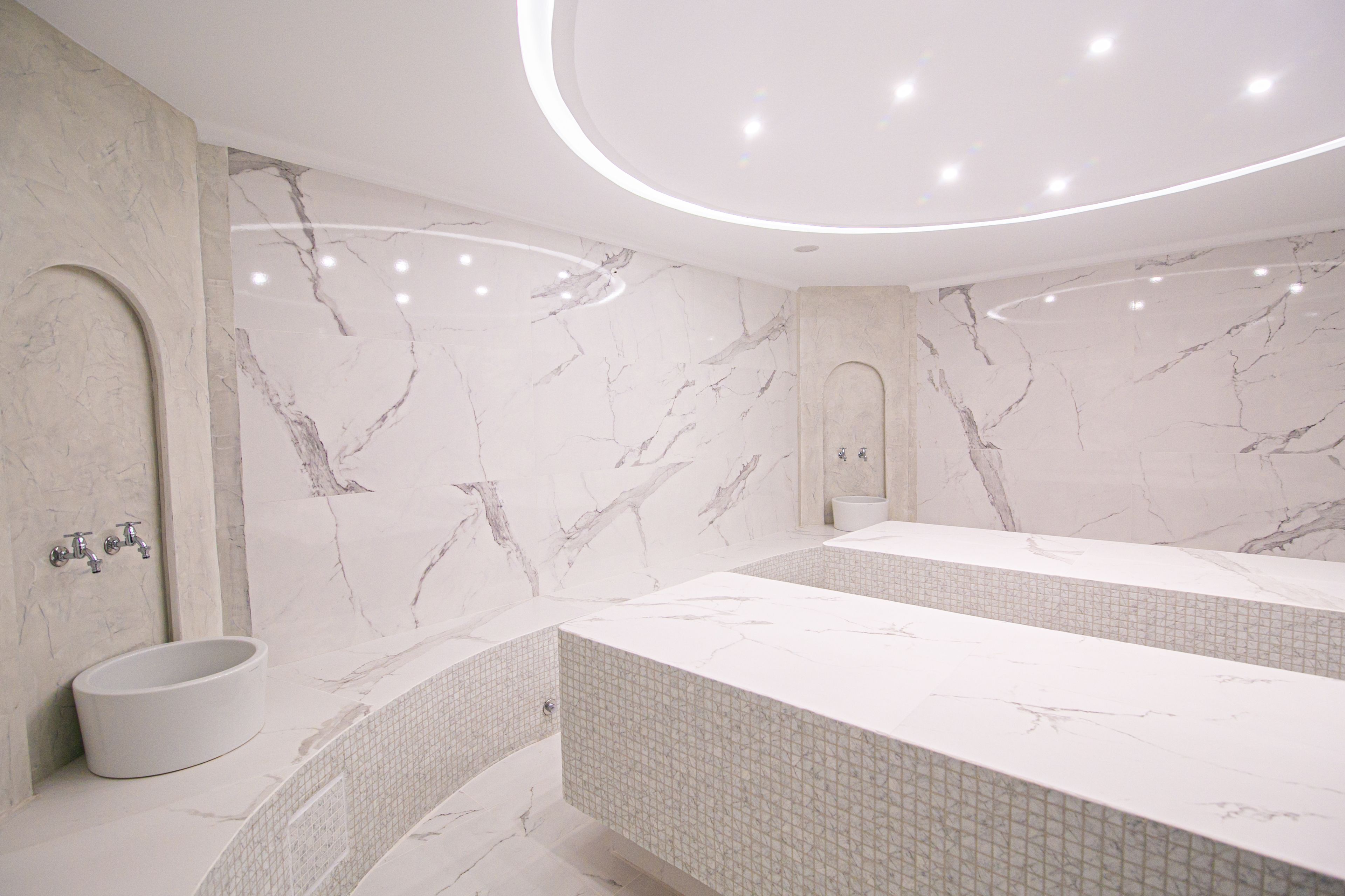 A modern bathroom with a marble vanity, a freestanding sink, and a tiled shower area.
