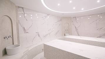 A modern bathroom with a marble vanity, a freestanding sink, and a tiled shower area.