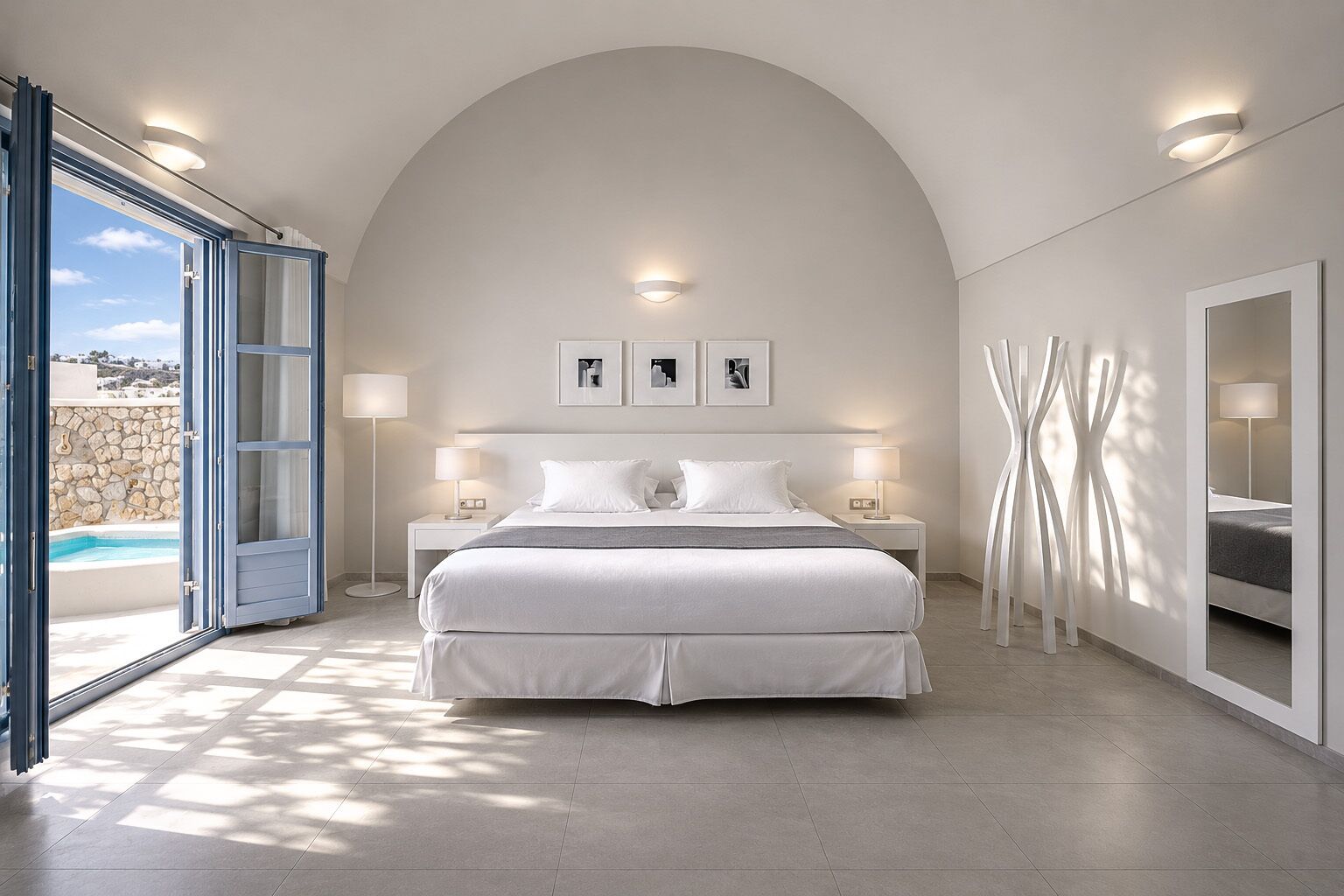 Quarto moderno com uma cama grande, duas mesas de cabeceira, vista para uma piscina e uma parede de pedra.