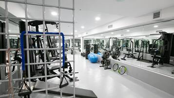 A gym with exercise equipment, a large mirror, and a blue exercise ball.