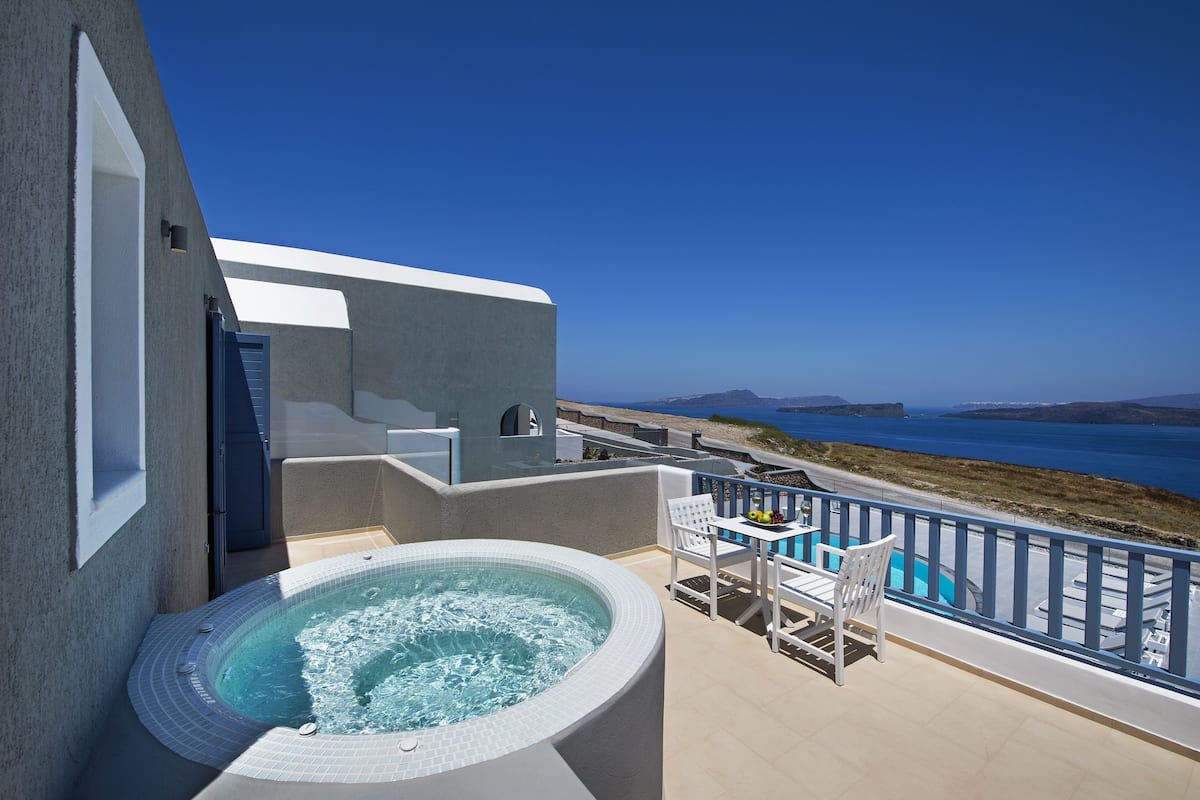 A balcony with a hot tub, outdoor seating, and a view of the sea.
