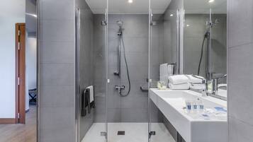 Une salle de bain moderne avec une douche à parois de verre, un lavabo blanc avec un miroir et un porte-serviettes.