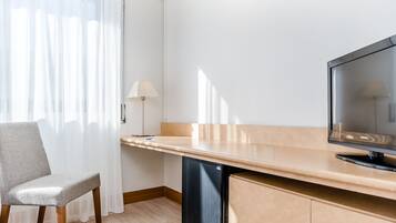 Una kitchenette compacta con refrigerador empotrado, una televisión de pantalla plana, una silla y una lámpara.