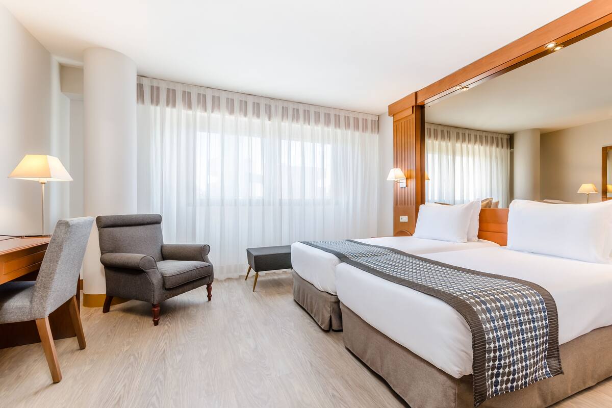 Une chambre d’hôtel avec un grand lit, un bureau, une chaise et une petite table.