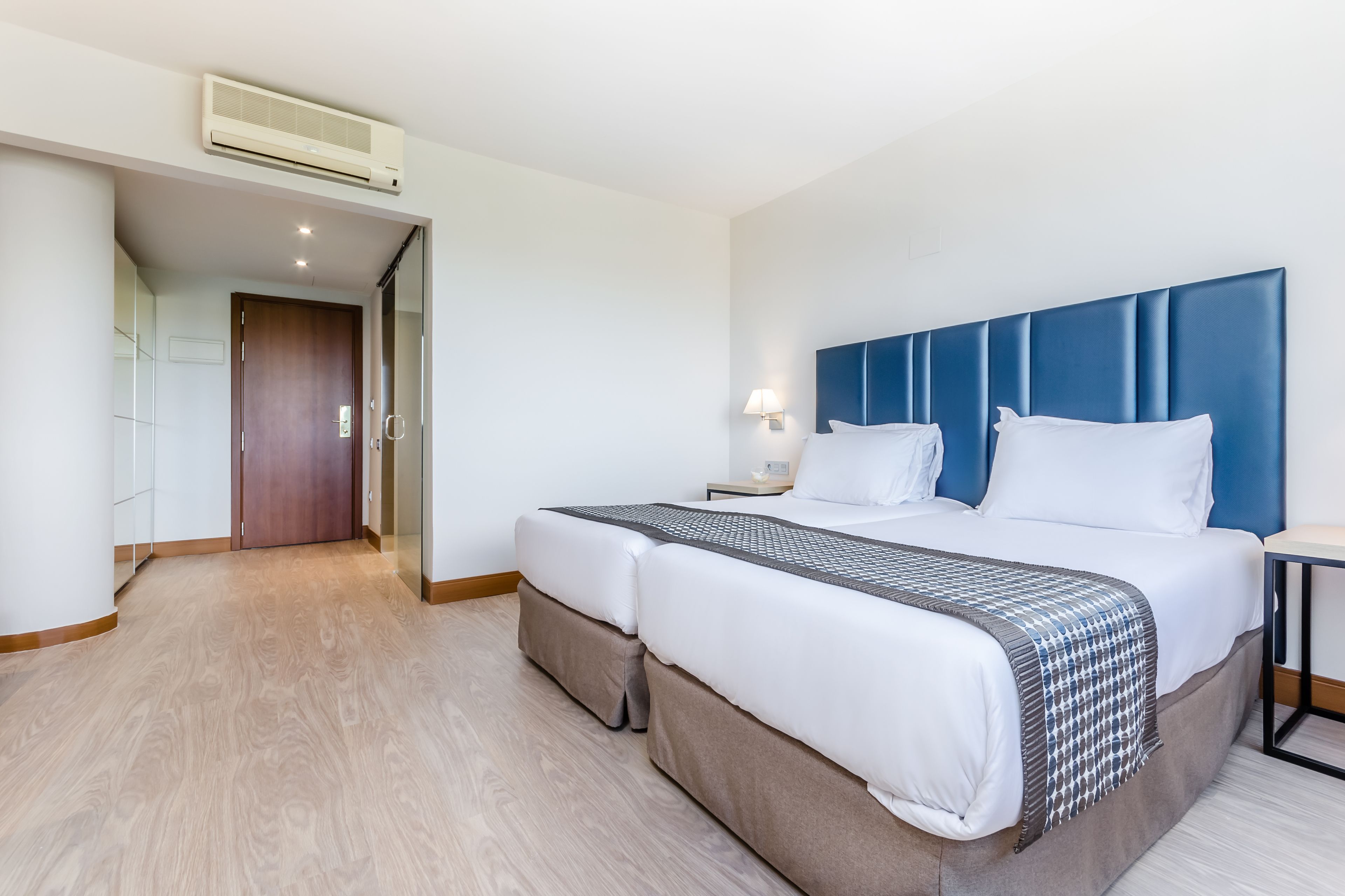 Een hotelkamer met een groot bed, een nachtkastje, een lamp en een kledingkast.