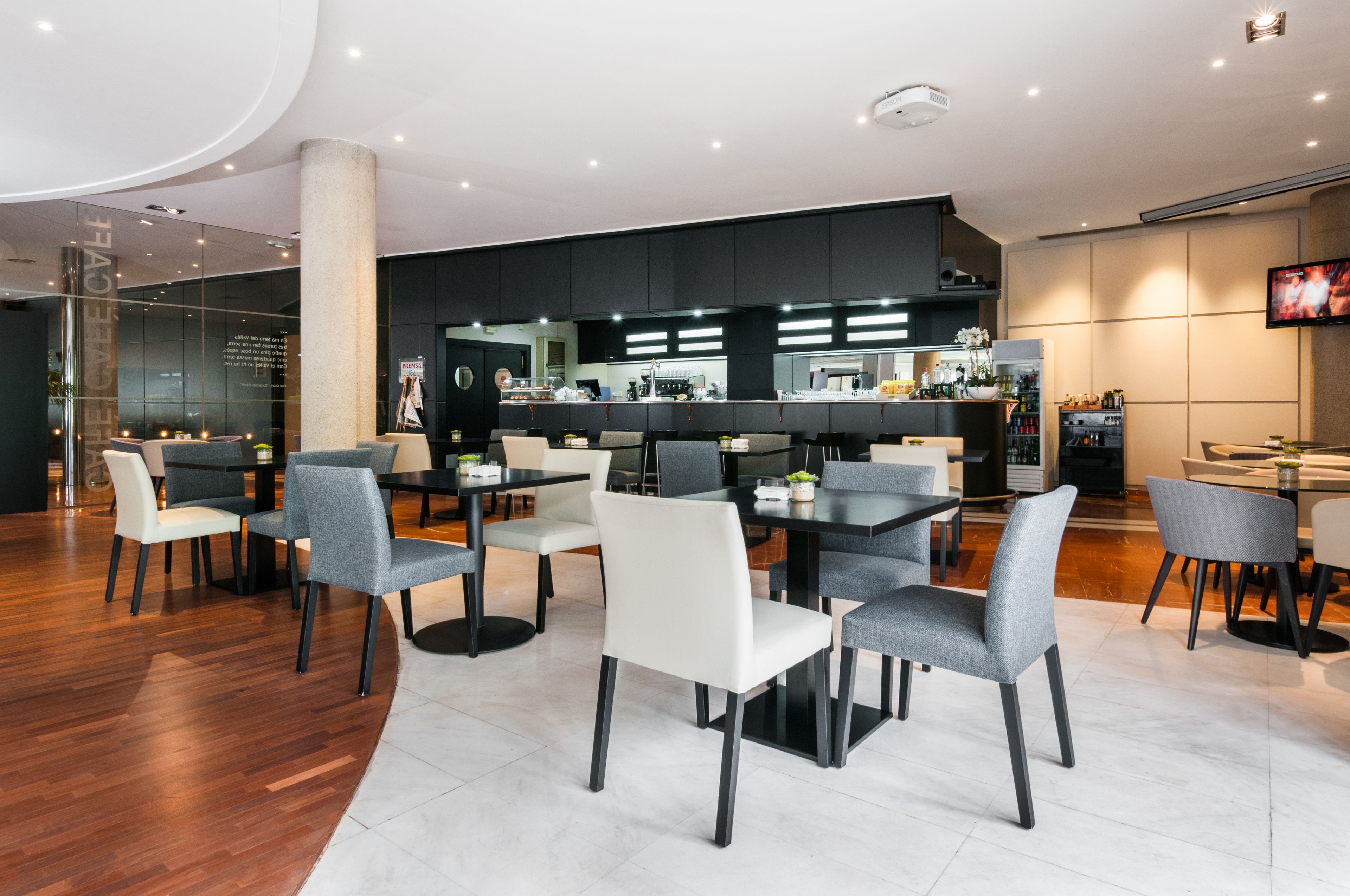 Un restaurante moderno con una barra central, varias mesas y sillas para comer.
