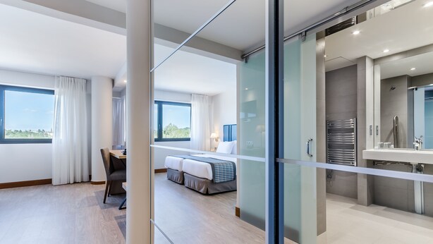 Una habitación de hotel moderna con una cama grande, un escritorio y vistas al exterior.