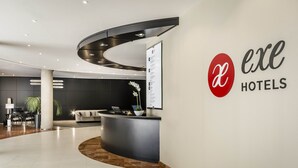 Un área de recepción moderna con un mostrador curvo, un gran cartel y una decoración minimalista.