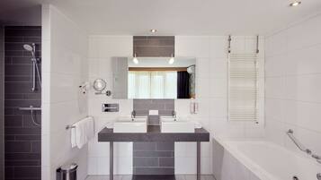 A modern bathroom with two sinks, a bathtub, and a shower.