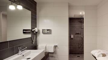 A modern bathroom with a large mirror, a sink, a shower area, and a towel rack.