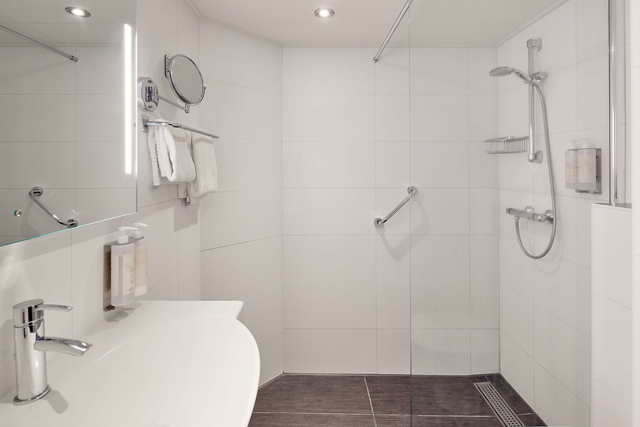 Een moderne badkamer met een douchecabine van glas, een wit wastafelmeubel en een spiegel.