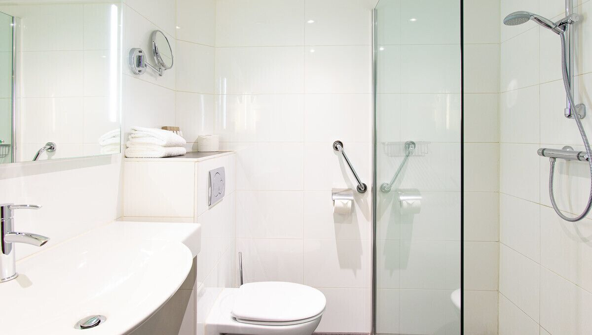 Une salle de bain moderne avec un lavabo blanc, des toilettes et une douche à parois de verre.