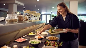 Montaje de bufé con diferentes alimentos y una persona sirviendo.