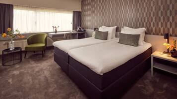 A hotel room with a large bed, a desk, a chair, and a view of the outdoors.