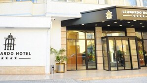The exterior of the Leonard Hotel with a modern entrance, a logo, and a clear glass facade. - Leonardo (Durres)