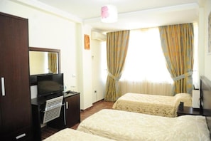 Habitación de hotel con dos camas, televisión, escritorio y armario.