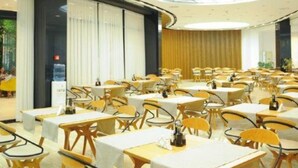 A hotel dining area with round tables, yellow chairs, and a modern ceiling design. - Leonardo (Durres)