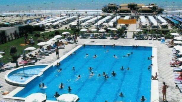 A large outdoor swimming pool with multiple lanes, surrounded by sun loungers and umbrellas. - Leonardo (Durres)