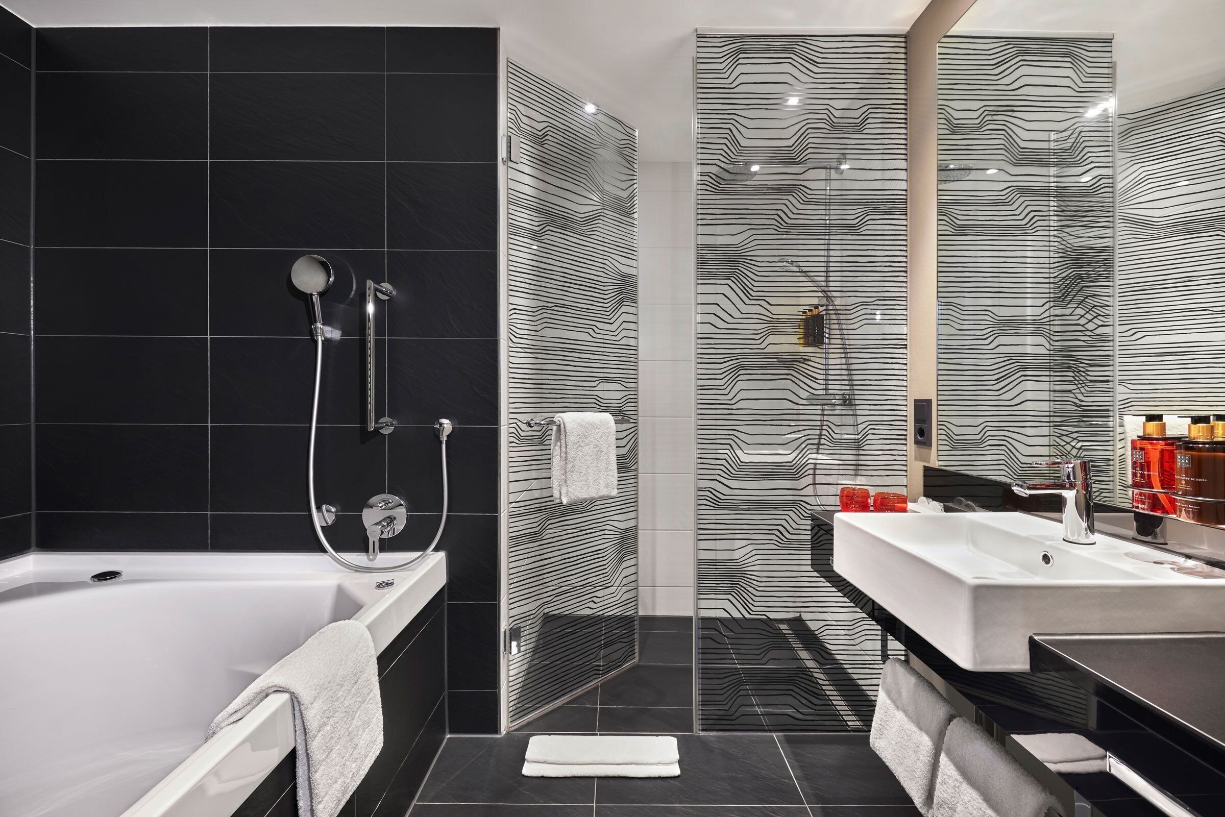 Ein modernes Badezimmer mit Badewanne, einer Duschkabine aus Glas und einem Waschtisch mit Waschbecken.
