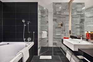 A modern bathroom with a bathtub, a glass shower enclosure, and a vanity with a sink. - LEGERE HOTEL Tuttlingen (Tuttlingen)