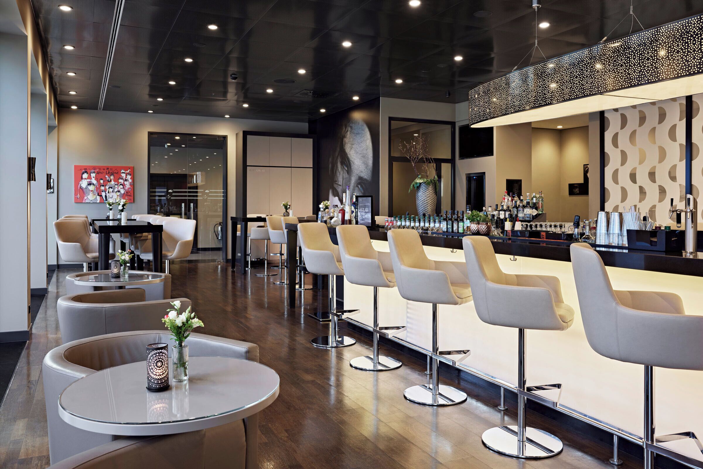 Een moderne bar met hoge krukken, een bar en een scherm waarop een afbeelding van een vrouw wordt weergegeven.