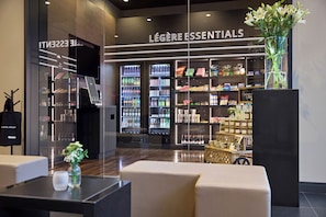A hotel lobby with a minibar, a minibar fridge, and a section labeled 'LÉGÈRE ESSENTIALS' with snacks and beverages. - LEGERE HOTEL Tuttlingen (Tuttlingen)