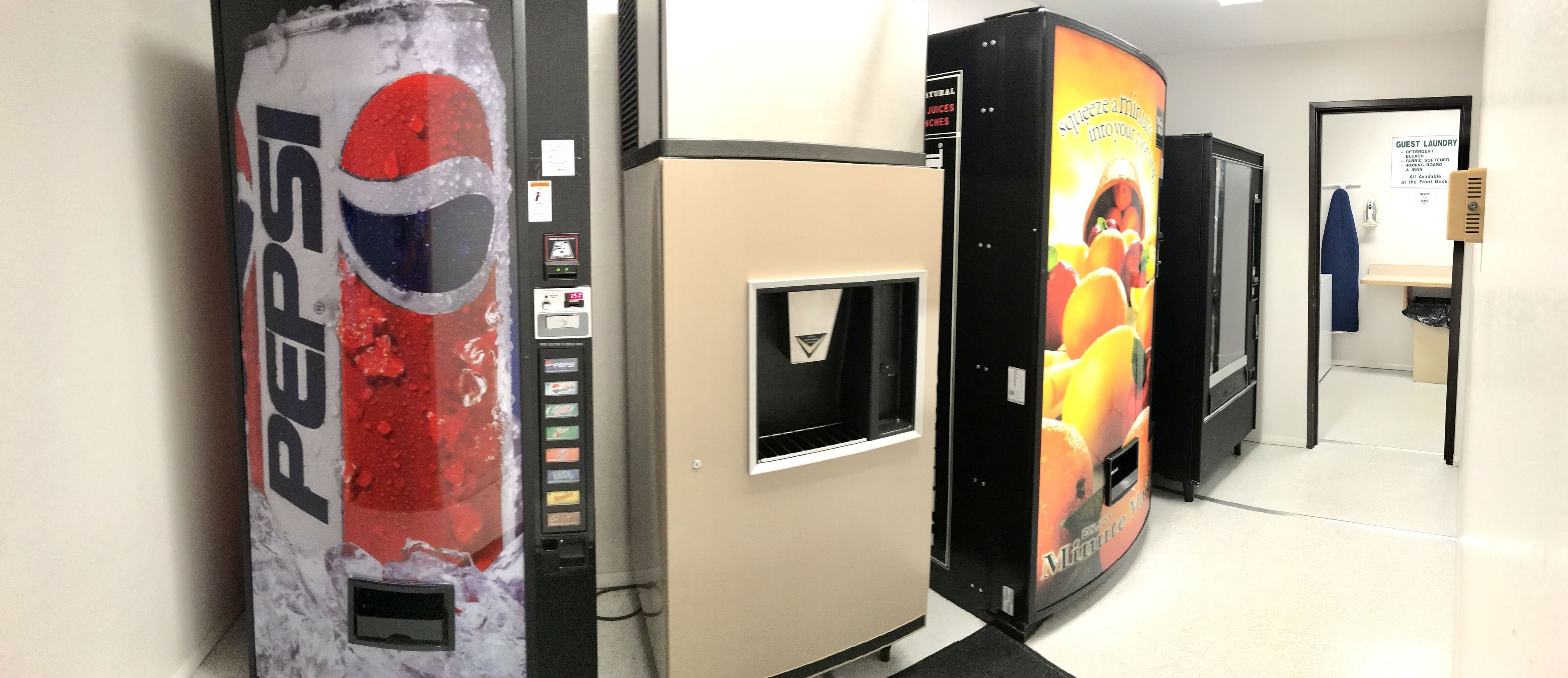 Des distributeurs automatiques dans un couloir, à proximité d’un panneau indiquant la laverie pour les clients.