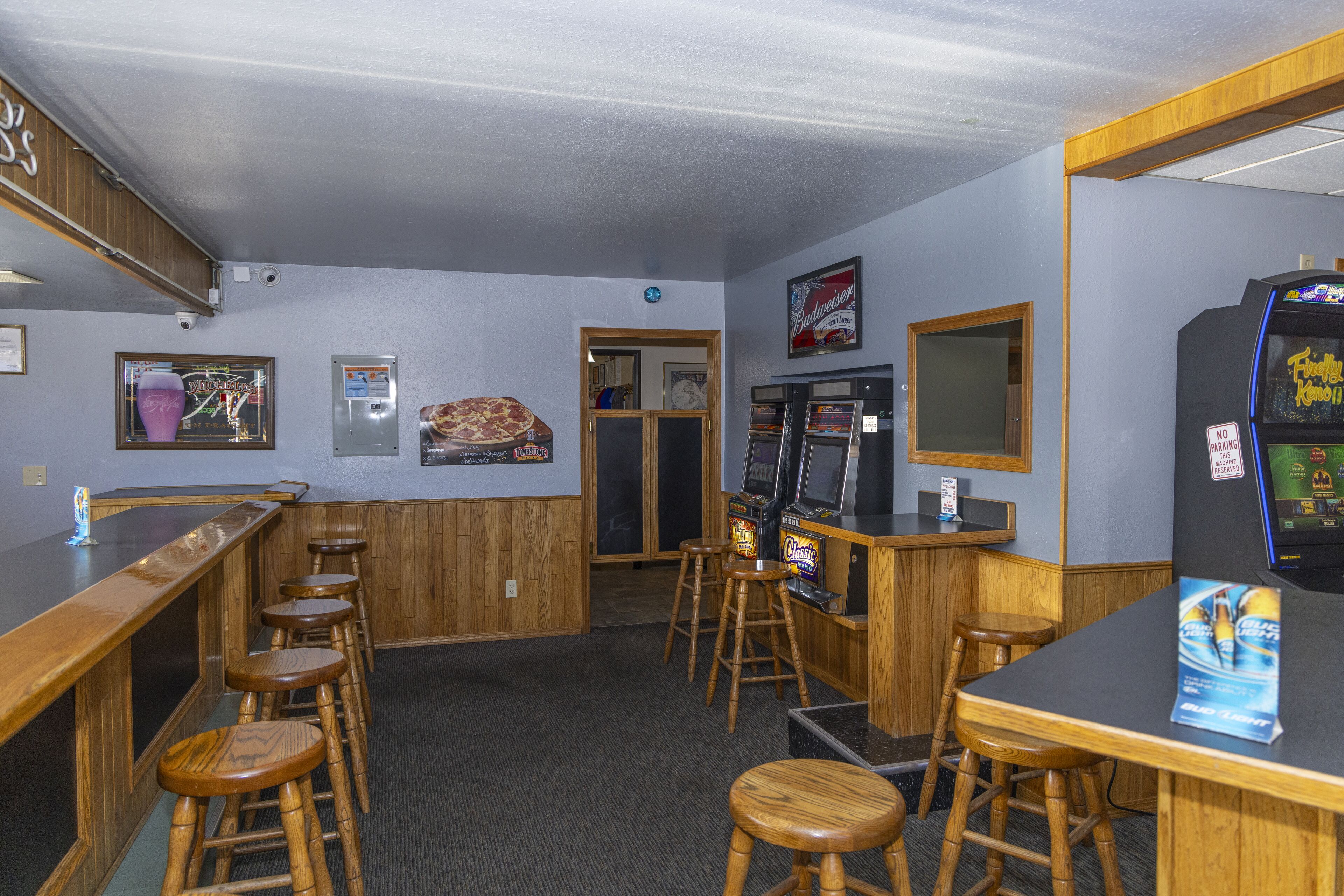 A bar area with wooden stools, a counter, and arcade machines.