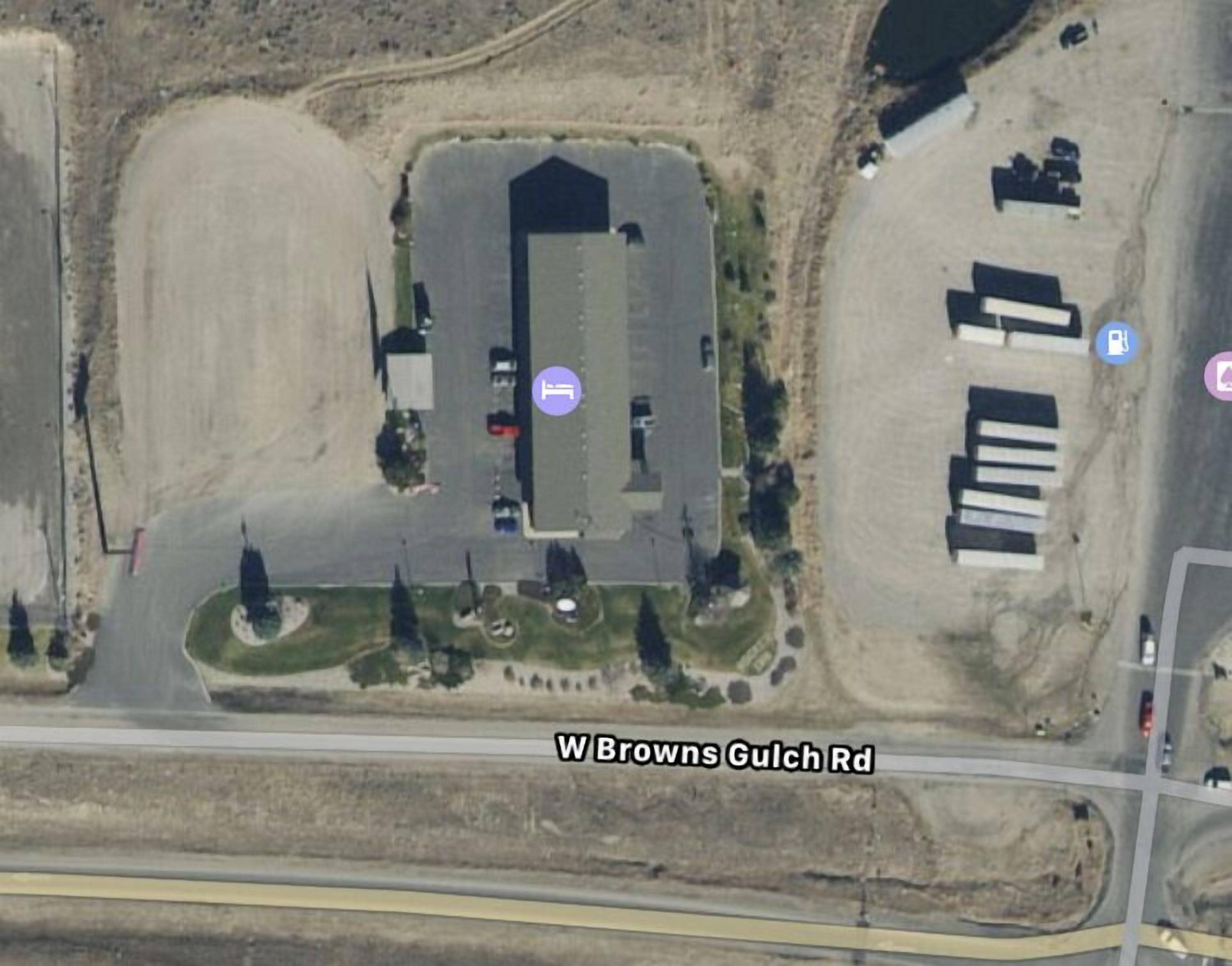 An aerial view of a commercial building with a parking lot, a gas station, and a road labeled W Browns Gulch Rd.