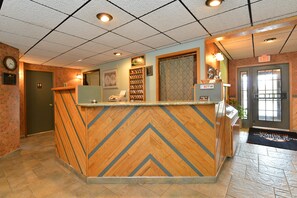 A reception desk with a herringbone wood pattern, a clock, and a wall-mounted phone.