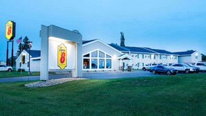 A Super 8 motel with a large sign, a parking lot, and a building with multiple windows.