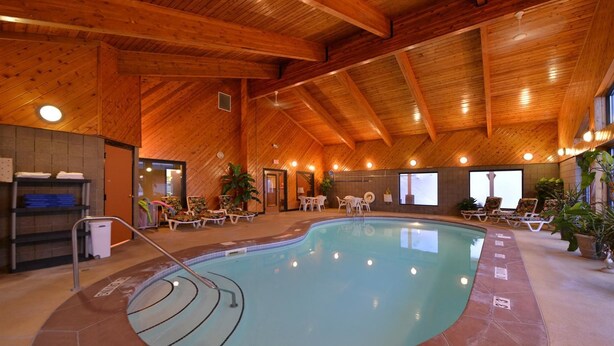 An indoor swimming pool with a wooden ceiling, lounge chairs, and a 'NO DIVING' sign.