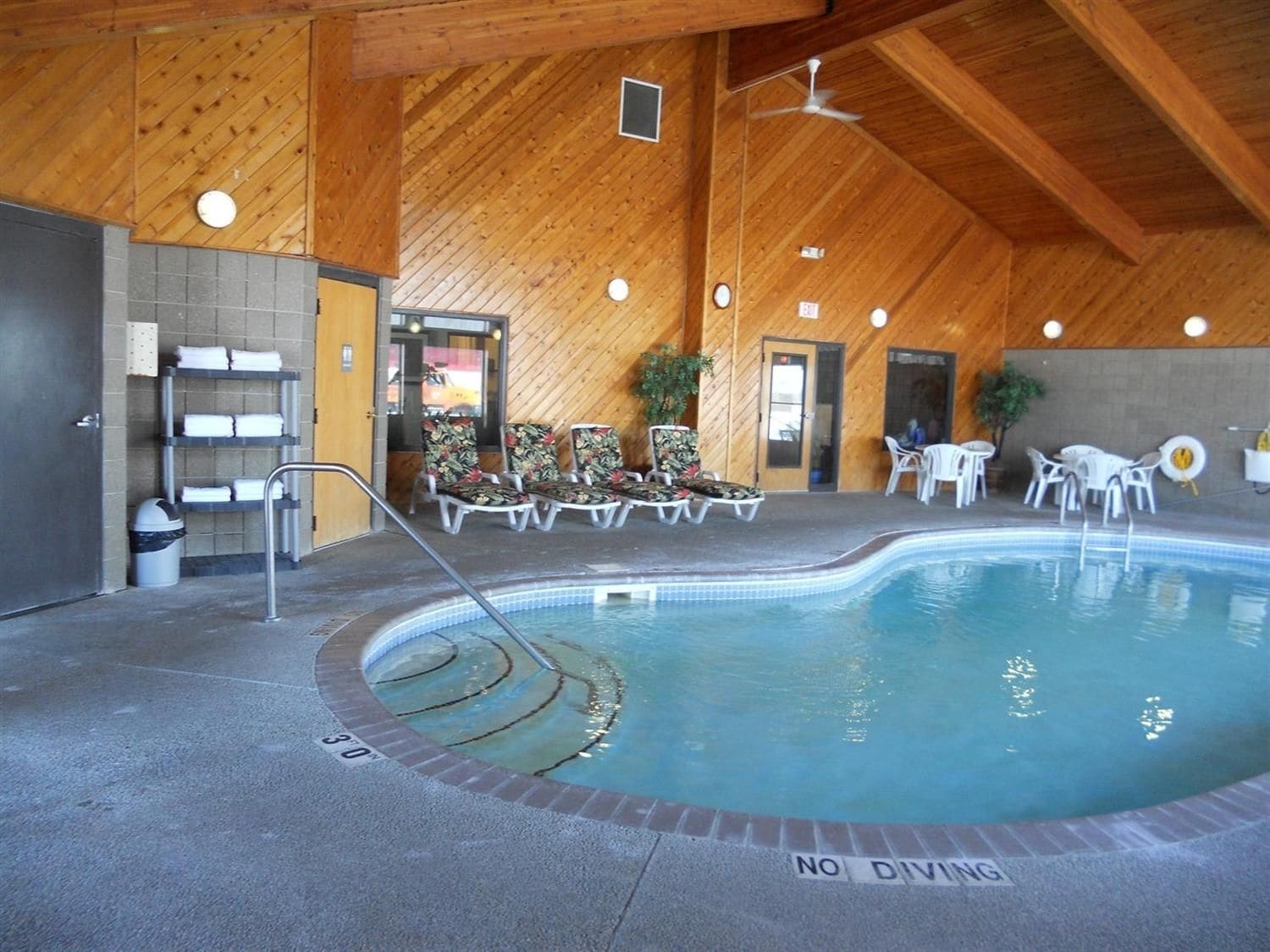 An indoor swimming pool with lounge chairs and a no diving sign.