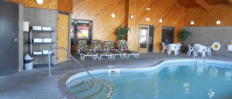 An indoor swimming pool with lounge chairs and a no diving sign.