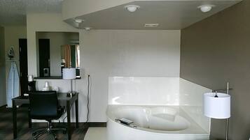 Une salle de bain moderne avec une grande baignoire, un bureau avec une chaise et un miroir.
