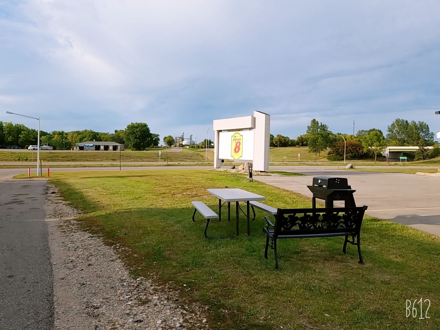 Un área de picnic con una banca, una mesa y un cartel de señalización al fondo.
