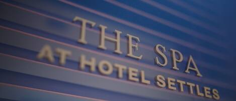 A sign for "The Spa at Hotel Settles" with horizontal lines in the background.