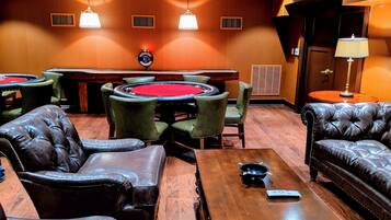 A casino room with leather chairs, a poker table, and a roulette table.