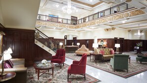 A spacious lobby with a grand staircase, multiple seating areas, and a chandelier. - Hotel Settles (Big Spring)