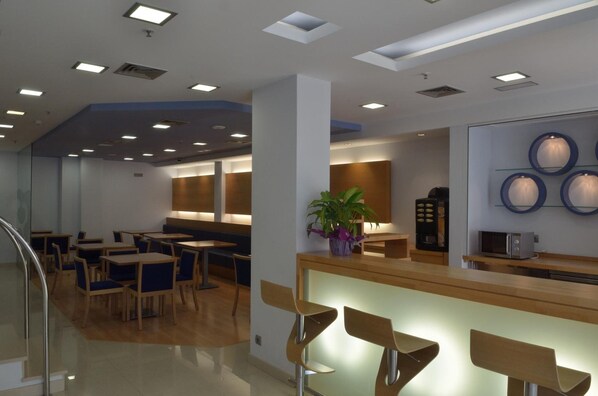 A modern dining area with tables and chairs, a reception desk, and a microwave.