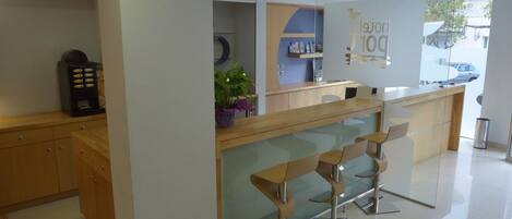 A modern reception area with a glass partition, wooden counter, and contemporary bar stools.
