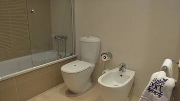 Een badkamer met toilet, bidet en bad.